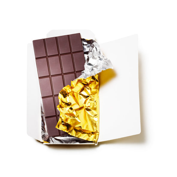 Chocolate bar wrapped in foil with open cardboard on white background